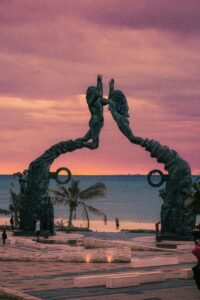 Beautiful sunset view of the Portal Maya Arch at Playa del Carmen with pink skies and ocean backdrop.